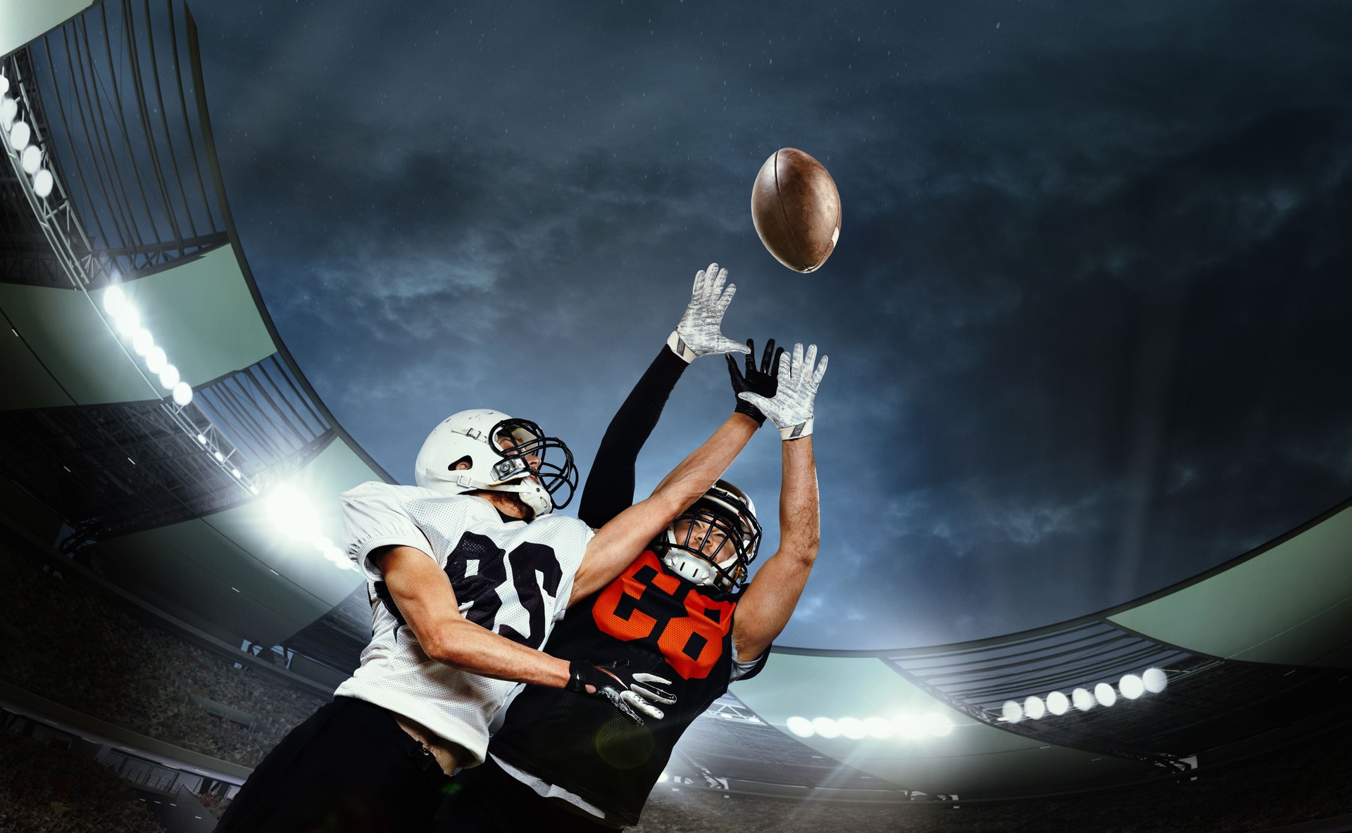Dynamische Aufnahme von männlichen Sportlern, professionellen American Football-Spielern während des Spiels, Fangball. Open-Air-3D-Stadion am Abend